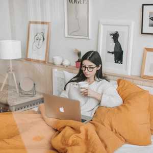 Woman in Bedroom Staring at Laptop underneath Plankets