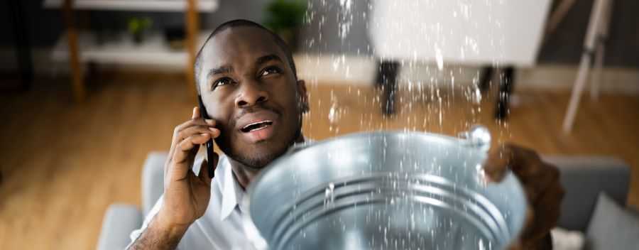 Man on the Phone Looking up at Water Sprinkling Into Bucket He Is Holding
