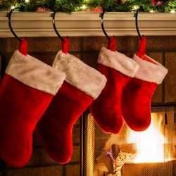 Red Christmas Stockings Hanging Over a Fireplace With a Lit Log Fire
