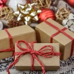 Christmas Presents Wrapped in Brown Paper and Red String With Decorations in the Background