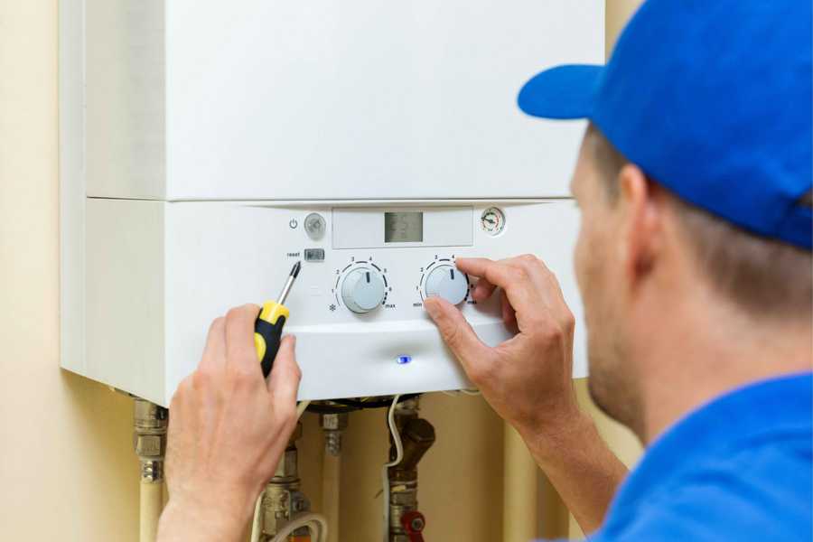 Engineer Fixing Boiler by Turning Controls