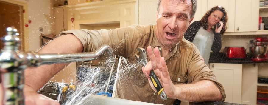 Water Spraying Man From a Kitchen Tap With a Concerned Woman Looking on Whilst Making a Call