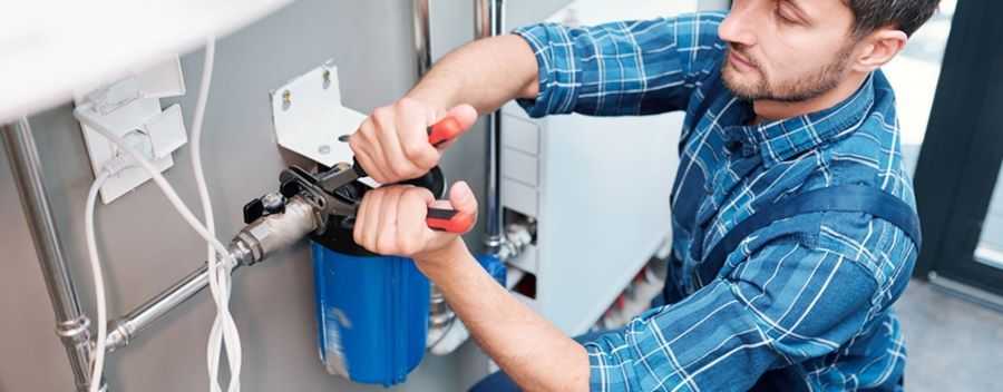 An Engineer in a Checkered Shirt Using a Wrench on a Pipe