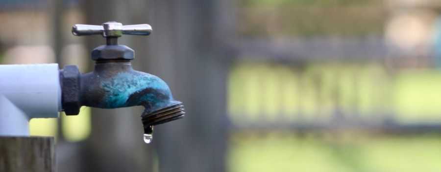 A Slow Dripping Outdoor Tap Over a Blurred Background 