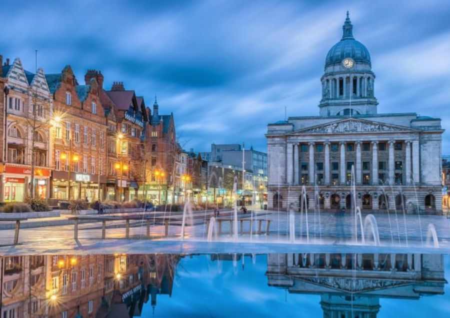 Nottingham Town Hall Clock in the Evening Overlooking Shops and Water Fountain With Jets and Tower Reflection